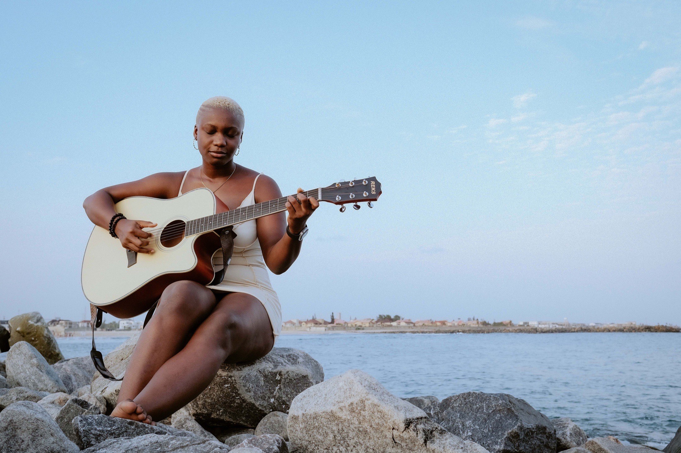 KKC playing guitar by the water.